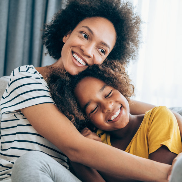young adult woman holding and smiling with her young daughter