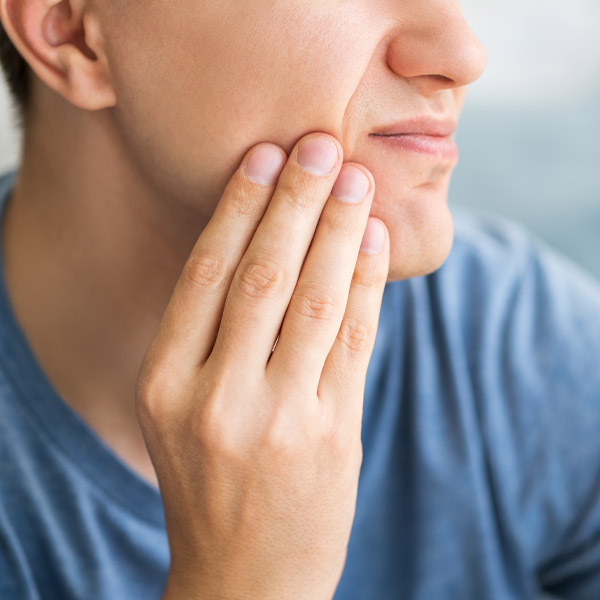man touching the side of his face in pain