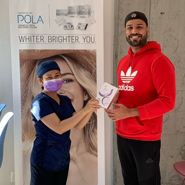 Dentist and patient holding teeth whitening system inside Fashion District Dental in Toronto