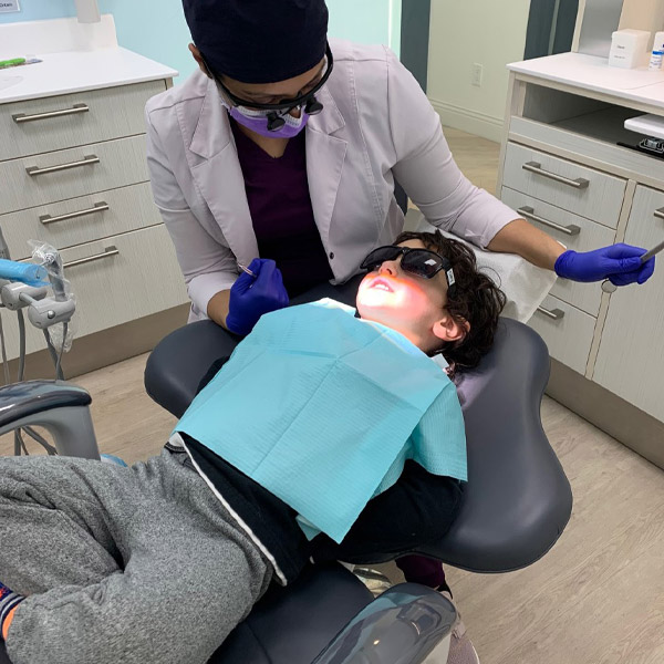 Dr. Monika with young boy in a dental exam chair at Fashion District Dental in Toronto